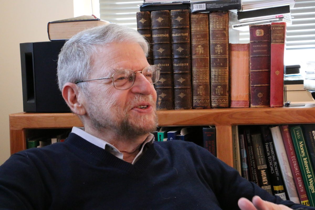 Arthur Goldhammer in conversation, seated before a bookcase holding volumes of Shakespeare, the Dictionnaire de l&rsquo;Acad&eacute;mie, and Renan.